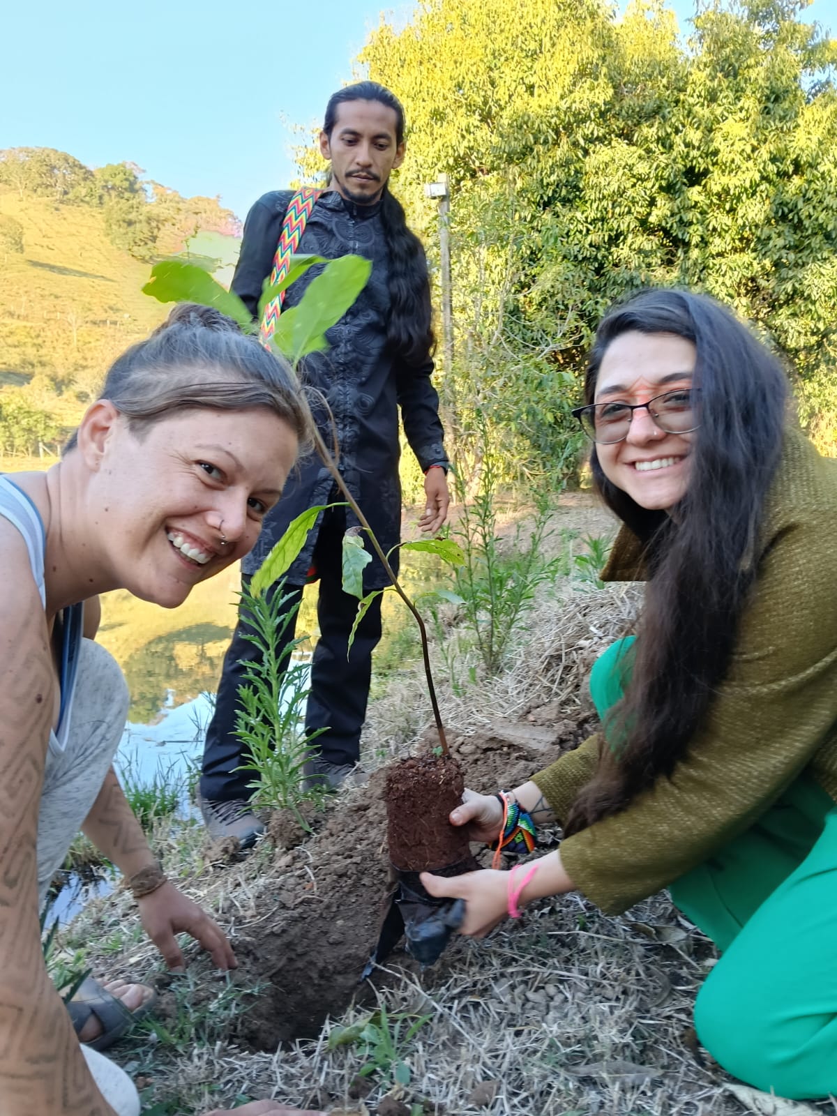 Participantes plantando uma muda à beira do lago